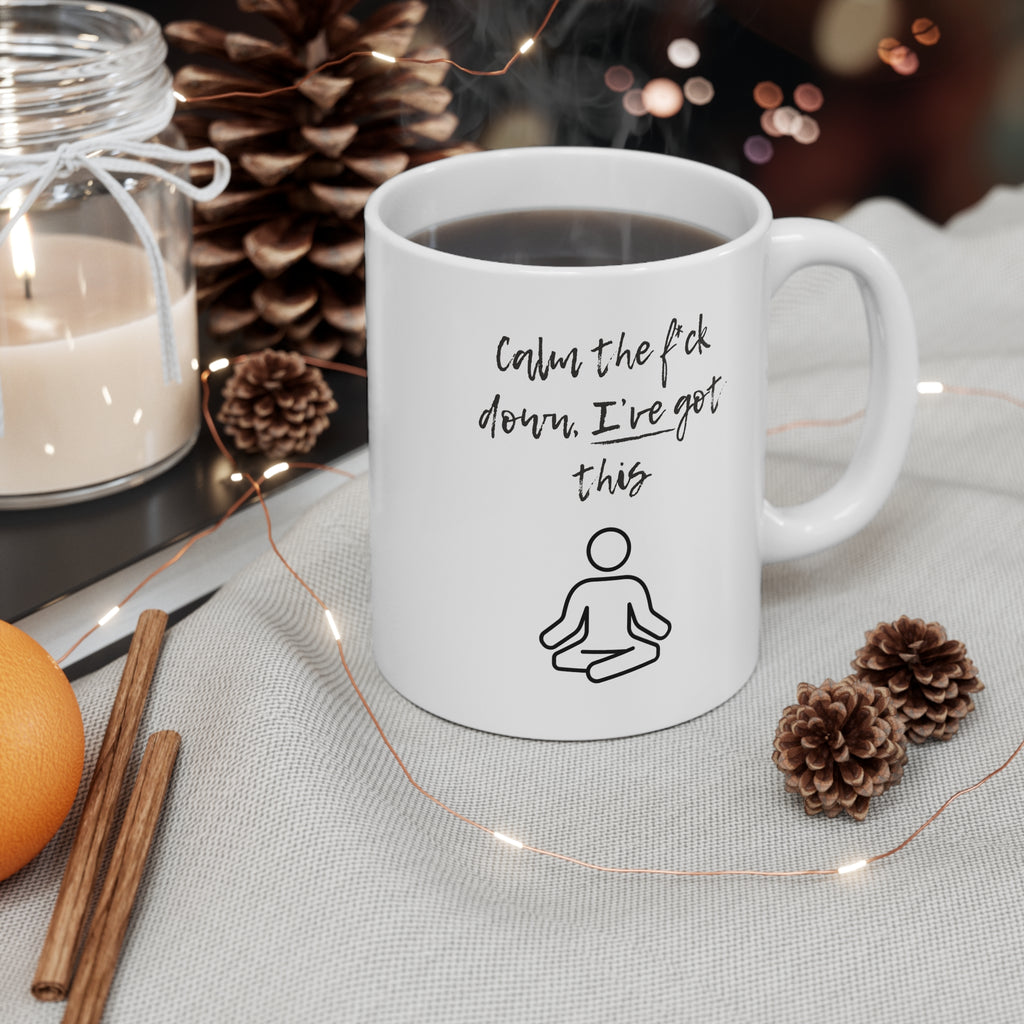 White mug with a black stick figure design on a table with decorative items