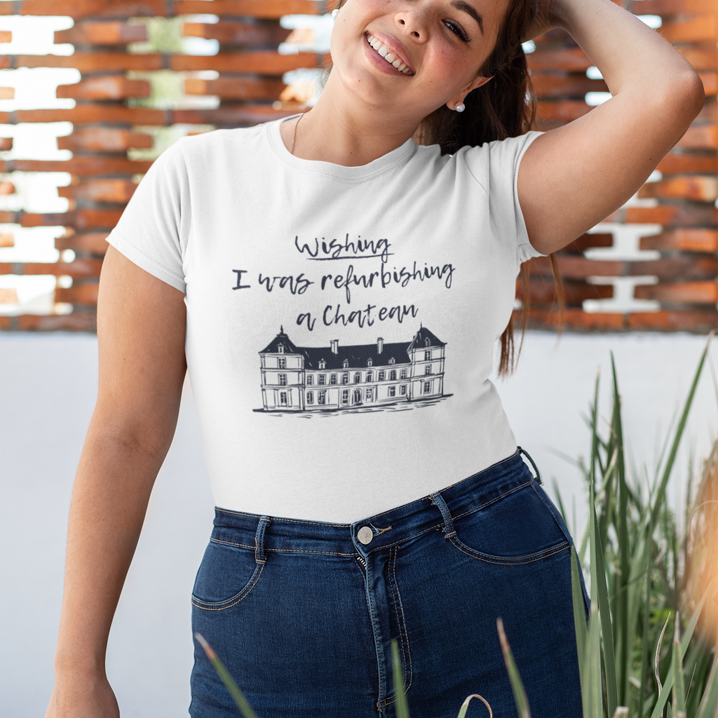 Woman wearing a  Pretty Bold Prints t-shirt with chateau refurbishing text laid out with cozy accessories. A perfect gift for ADHDers and dreamers who love home renovation shows