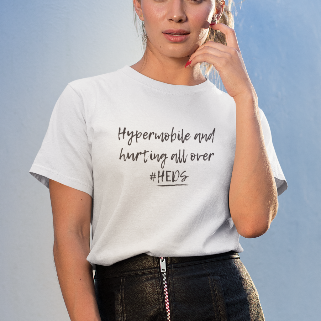 Woman wearing a white t-shirt with text 'Hypermobile and hurting all over #HEDS' and a black leather skirt against a light blue background