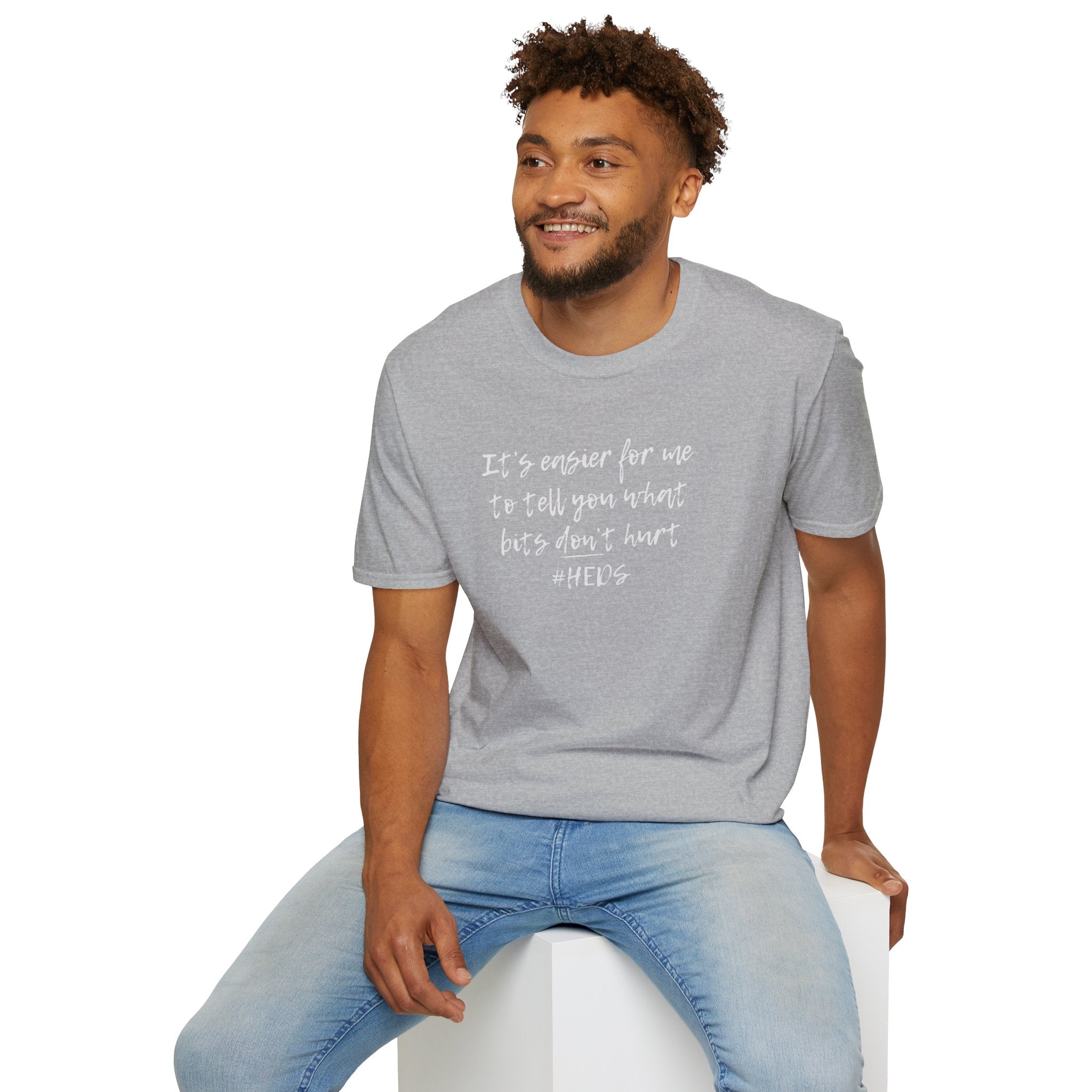 Man wearing a gray t-shirt with heds quote sitting on a white stool.