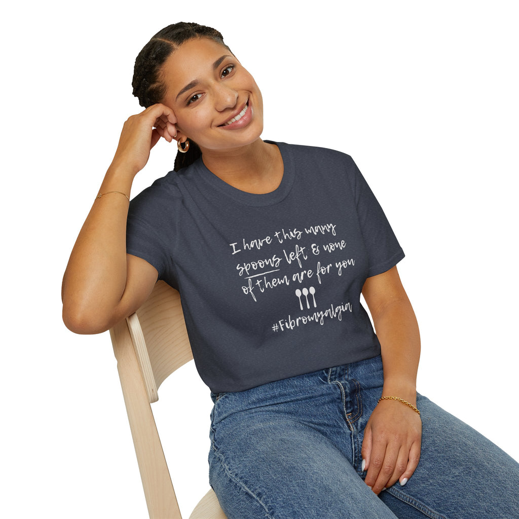 Woman wearing a navy blue t-shirt  featuring three hand-drawn spoons and the text "I Have This Many Spoons Left and none of them are for you." An empowering, relatable design for Fibromyalgia and Spoonie life. graphic sitting on a chair.